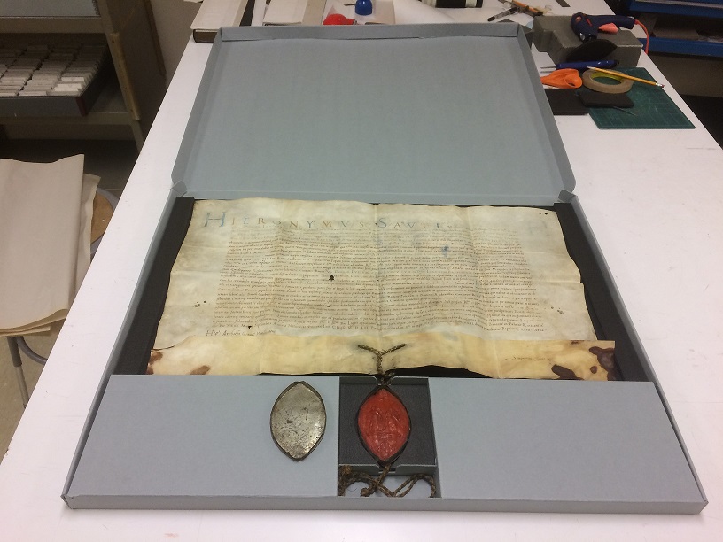 White parchment document with text inside an opened blue storage box.